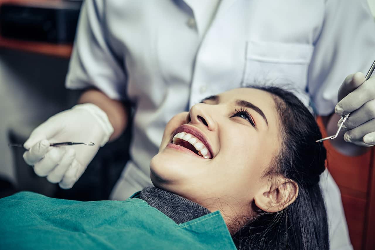 woman laid down in dentist chair and smilling