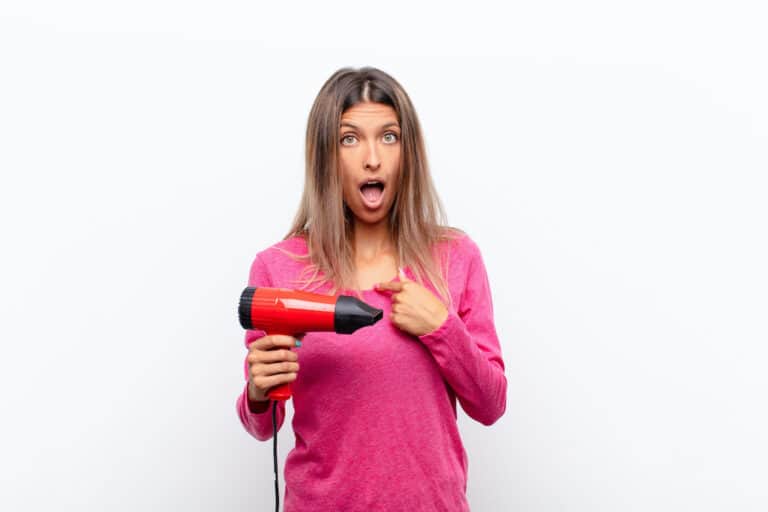 woman with hairdryer pointing herself