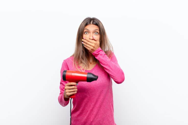 woman holding hairdryer covering mouth