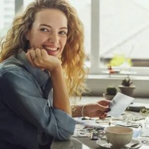 blond curly hair woman smilling holding photographs