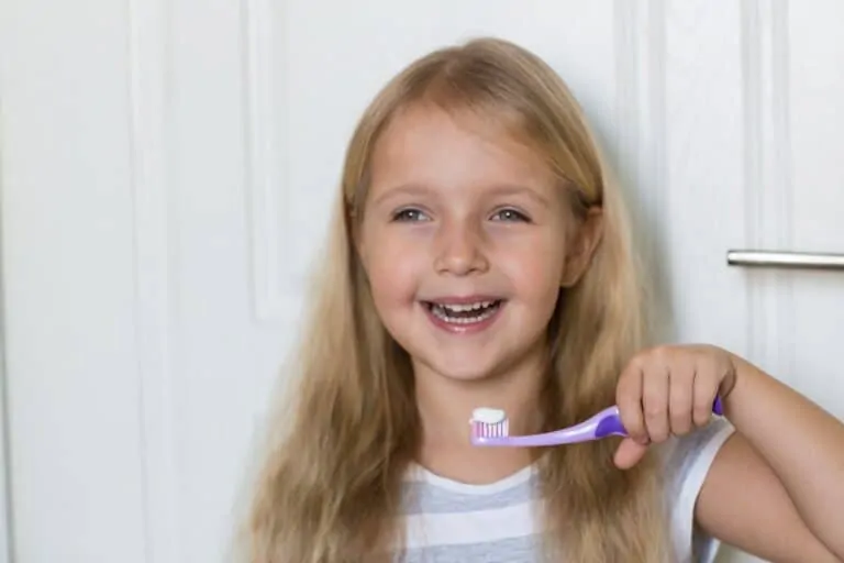 Kid smilling with a toothbrush and toothpaste