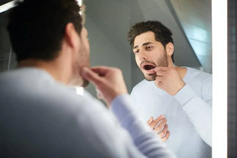 young man checking tooth in bathroom