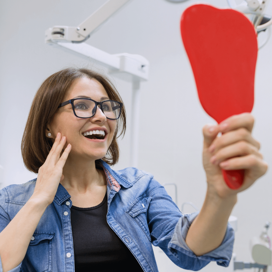 Woman looking at mirror amazed by dental result